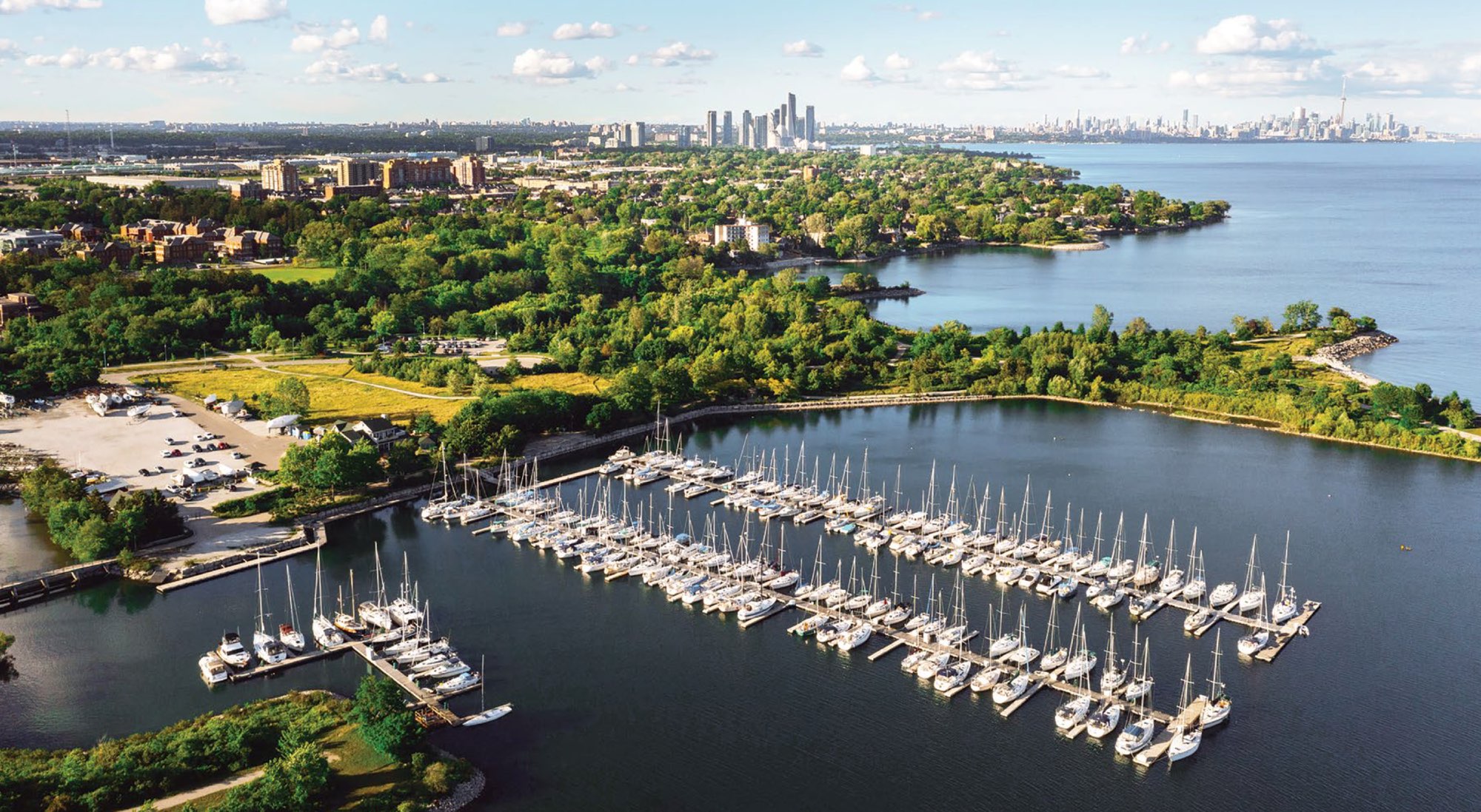 Aerial view of Lakefront Promenade Marina full of sailboats, with the Toronto skyline on the horizon