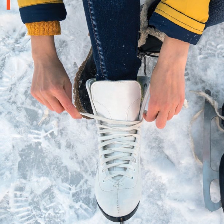 Close-up of hands lacing a white skate on outdoor ice